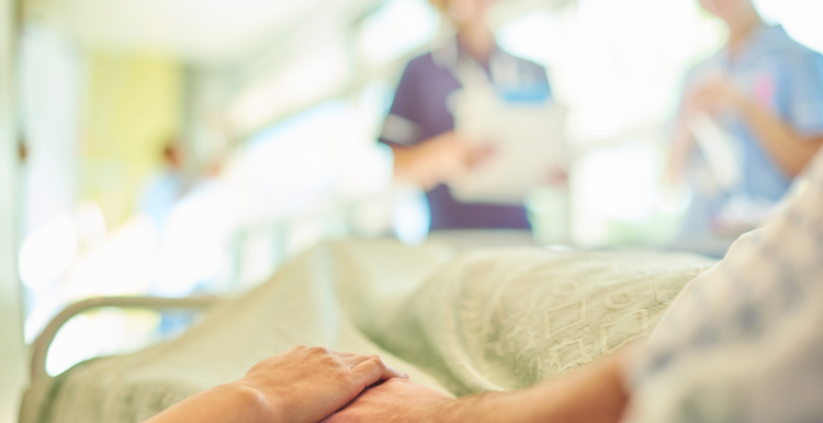 Patient on hospital bed holding hands with a relative