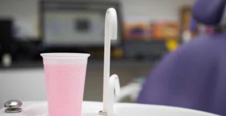 A cup of pink liquid and a tap in a dentist's room