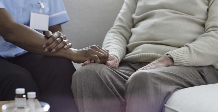 A nurse holding an older man's hand