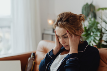 Lady sitting on a chair, with her hands on her head looking frustrated