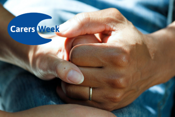 Two people's hands clasped together to provide comfort. Logo for Carers Week in the top left corner.